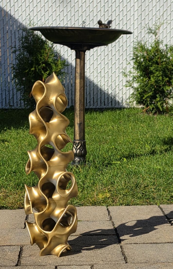 Colonne sculpturale dorée — feuilles empilées, installation extérieure